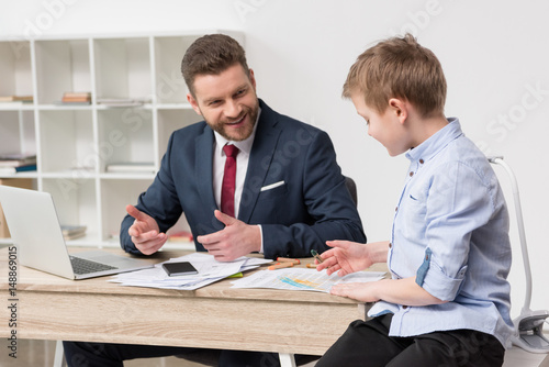 Businessman with his son drawing on business papers at office