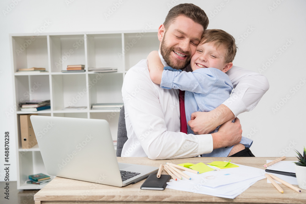 Businessman hugging with son at office Businessman hugging with son at office