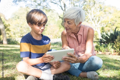 Grandmother and grandson using digital tablet in the park