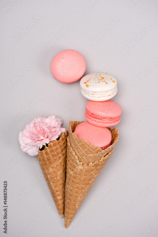 Group of pink macarons styling with waffle cones and flower. Still life of macarons concept Group of pink macarons styling with waffle cones and flower. Still life of macarons concept