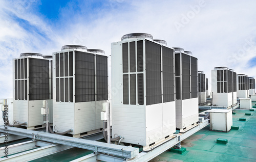 A row of air conditioning units on rooftop with blue sky