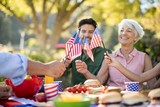Family holding American flags while having meal in the park