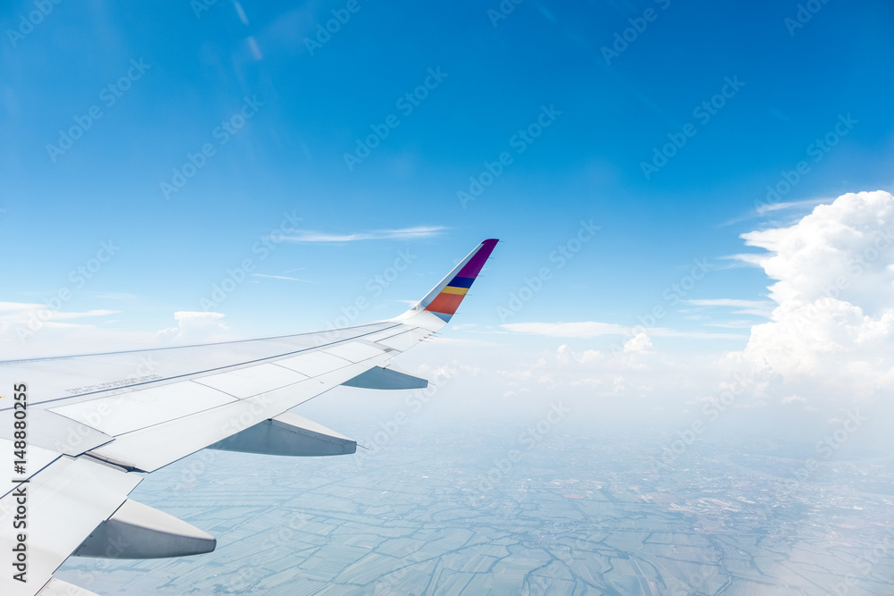 Fototapeta premium Wing of an airplane flying above Clouds