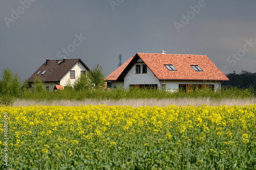 New house in the country behind the field of the rapeseed