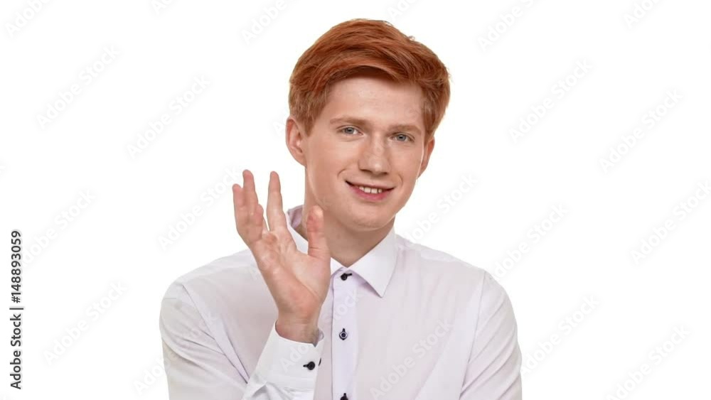 Young handsome Caucasian ginger man calmly standing on white background and slowly waving hand in slowmotion Young handsome Caucasian ginger man calmly standing on white background and slowly waving hand in slowmotion