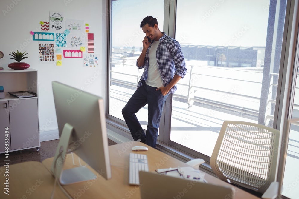 Male graphic designer talking on phone in creative office Male graphic designer talking on phone in creative office
