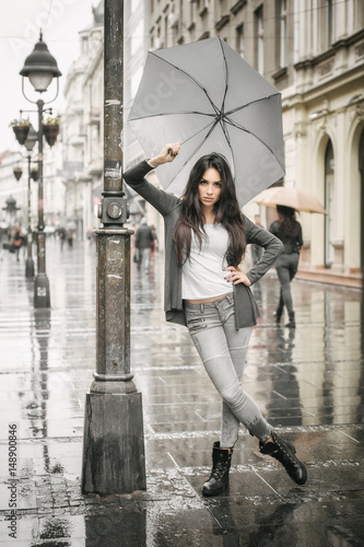 Woman with an umbrella under rain on a city street