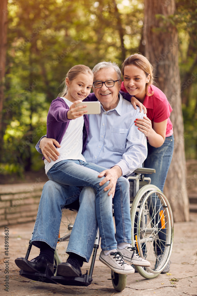 family selfie time- granddaughter, daughter and disabled man in wheelchair . family selfie time- granddaughter, daughter and disabled man in wheelchair .