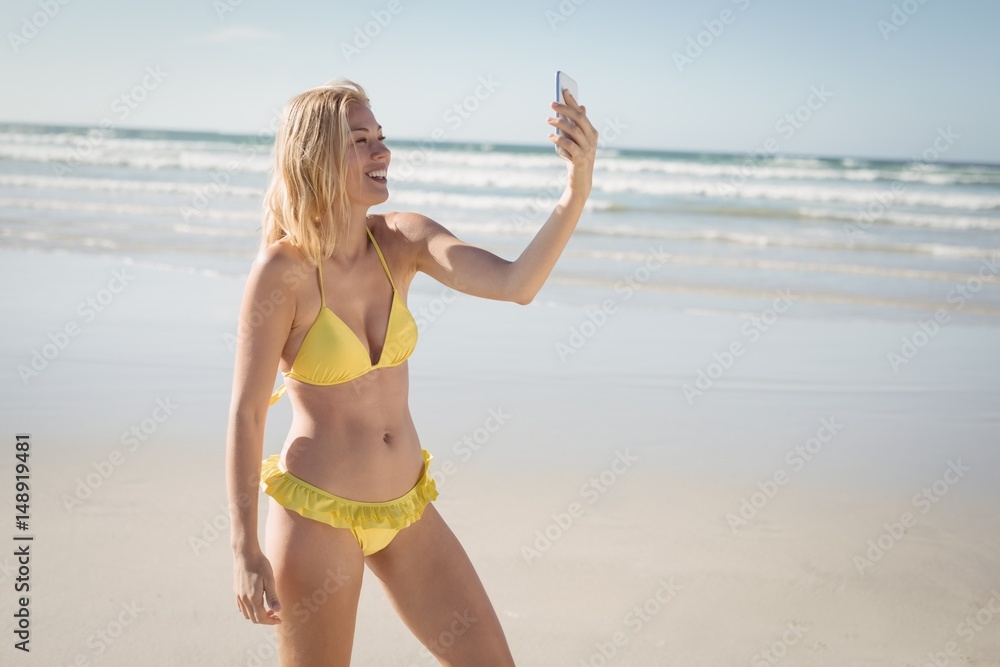 Happy young woman in yellow bikini taking selfie at beach Happy young woman in yellow bikini taking selfie at beach