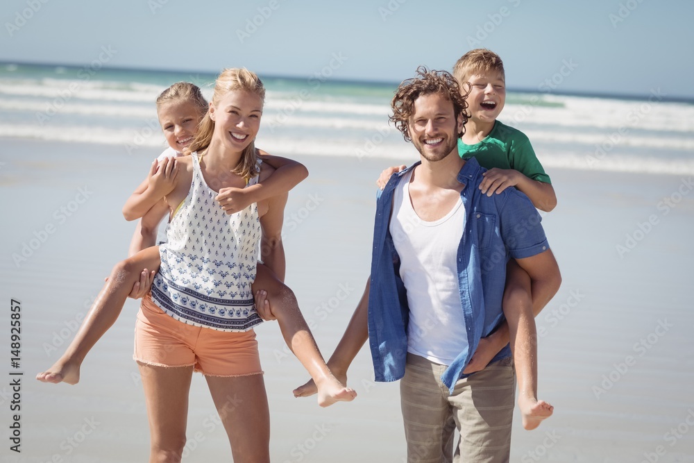 Portrait of happy parents piggybacking their children at beach Portrait of happy parents piggybacking their children at beach