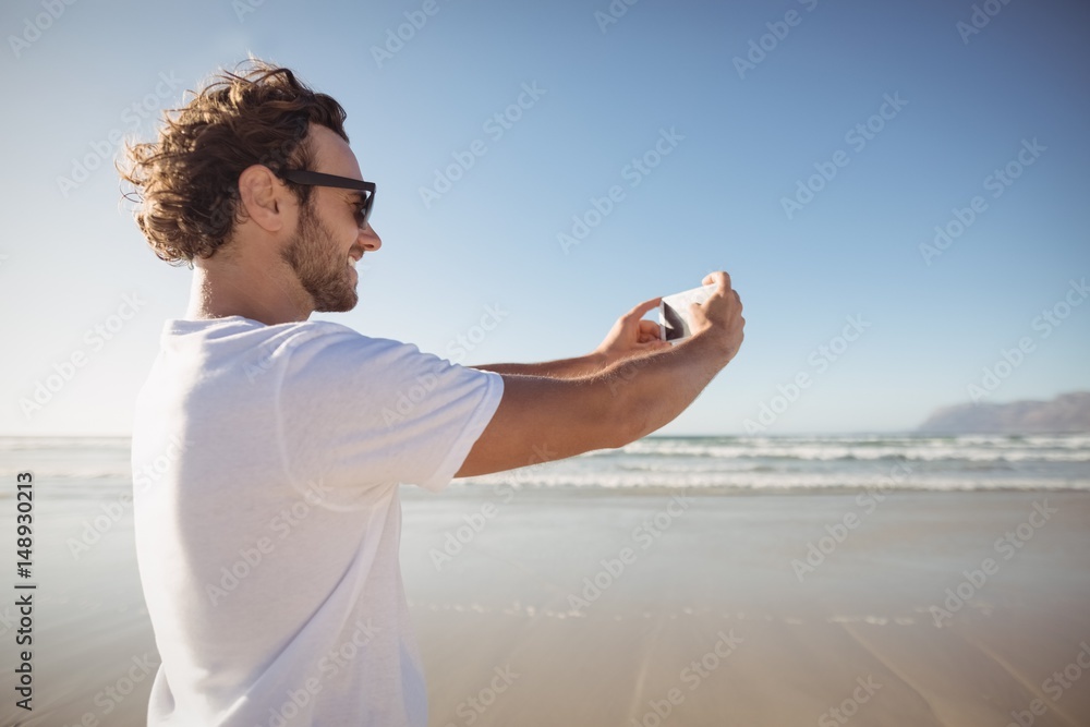 Happy man taking selfie against blue sky at beach Happy man taking selfie against blue sky at beach