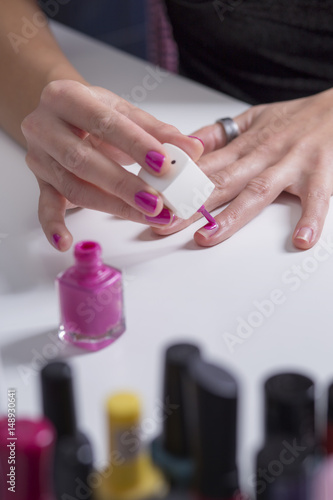 Girl paints her nails with pink nail polish