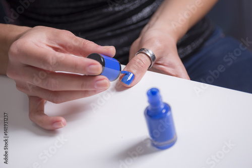 Girl paints her nails with blue nail polish