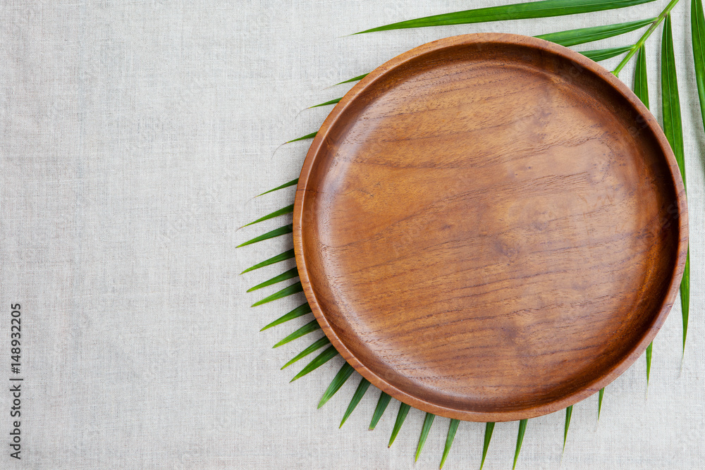 Wooden plate with palm leaf. Copy space. Top view. Wooden plate with palm leaf. Copy space. Top view.
