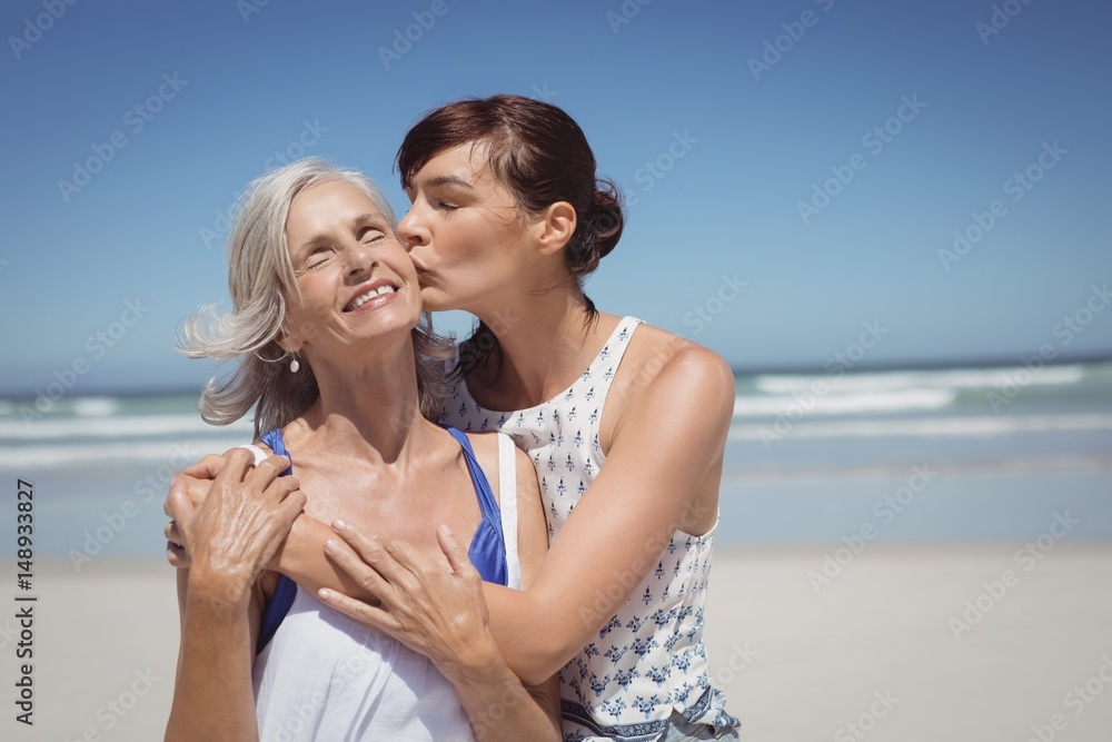 Young woman kissing her mother at beach