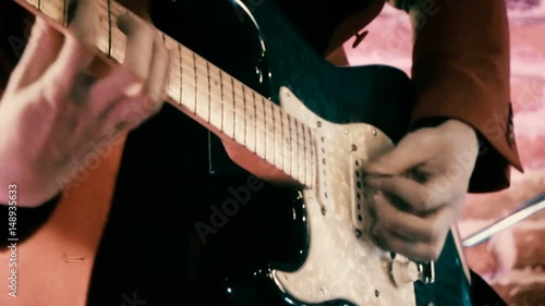 Guitarist on stage playing drums and guitar and singing in front of brick wall defocused footage