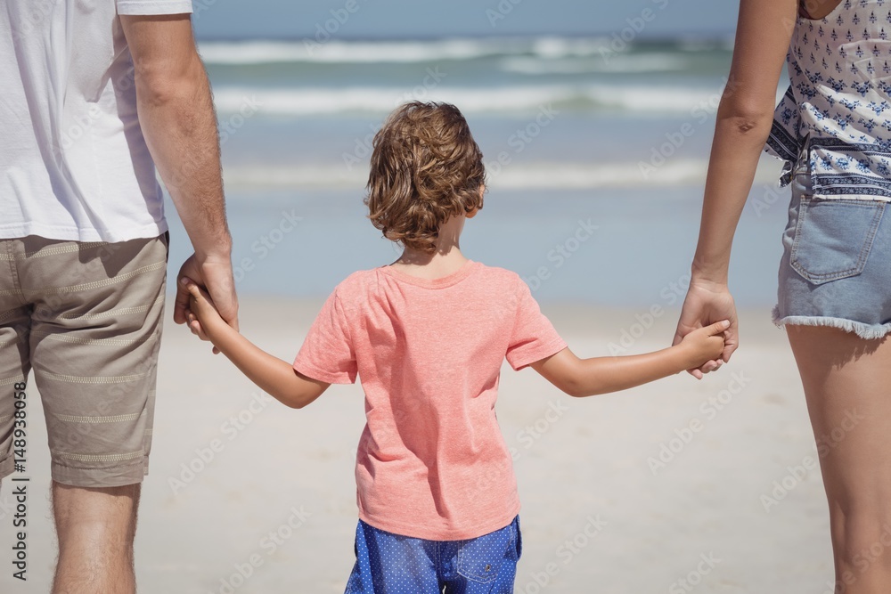 Rear view of boy holding hands with parents Rear view of boy holding hands with parents