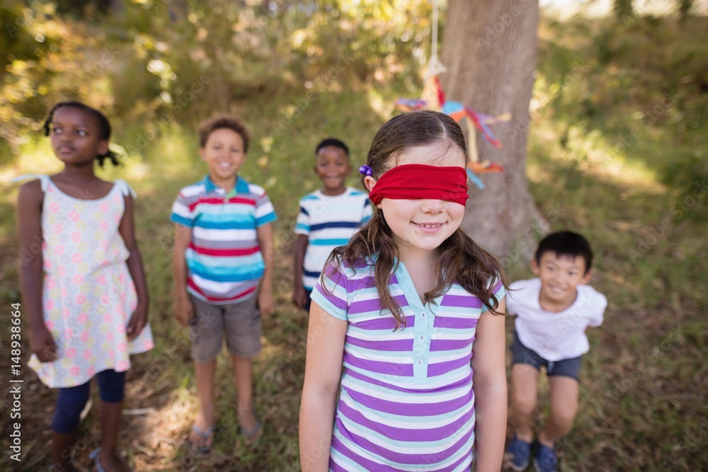 Fototapeta premium Friends looking at blindfolded girl standing in forest