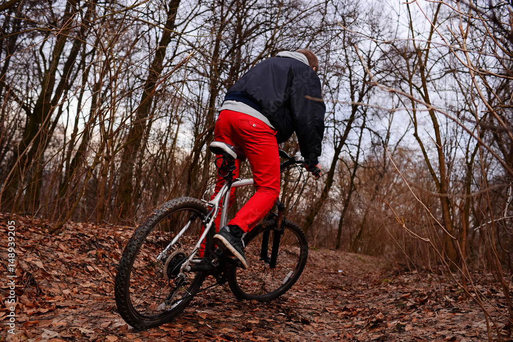 young man with backpack riding bicycle on mountain road in the forest young man with backpack riding bicycle on mountain road in the forest