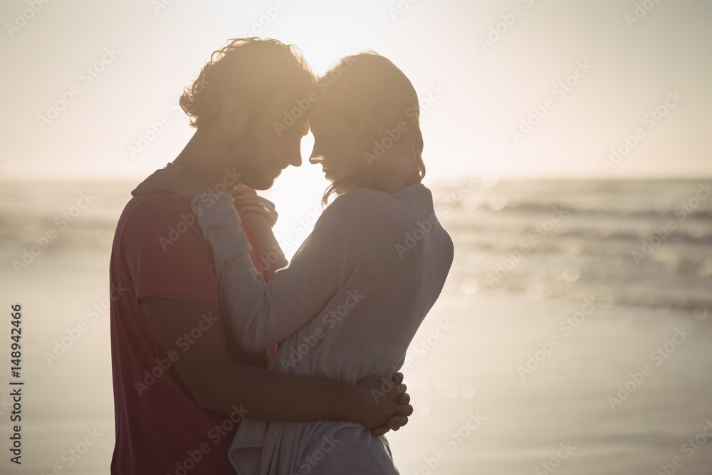 Side view of couple embracing at beach