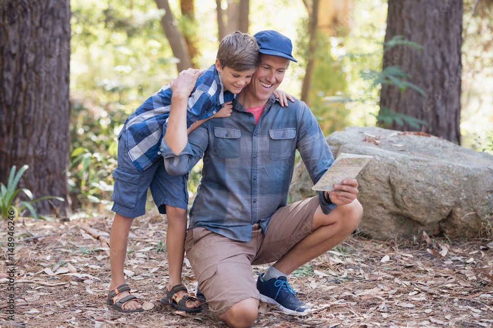 Father and son reading map while hiking in forest Father and son reading map while hiking in forest