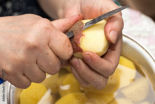 The cook cleans the potatoes with a knife