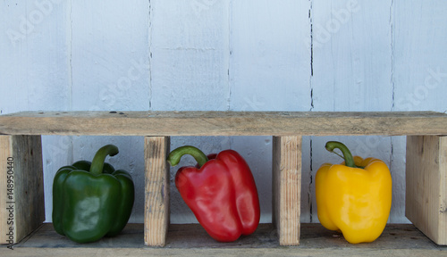 Red green and yellow peppers wooden shelf