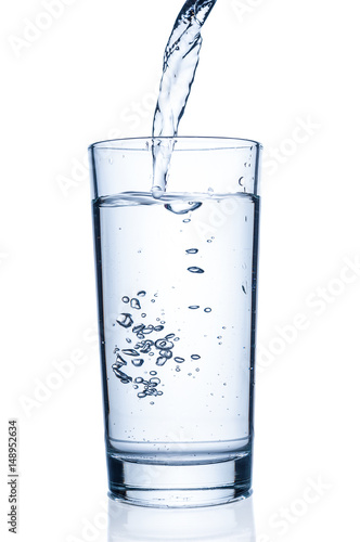 Pouring water into glass on white background