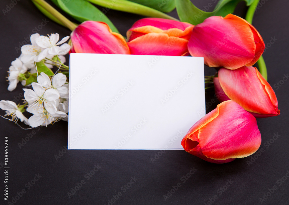 Fototapeta premium a sign on a black background with red tulips and white flowers
