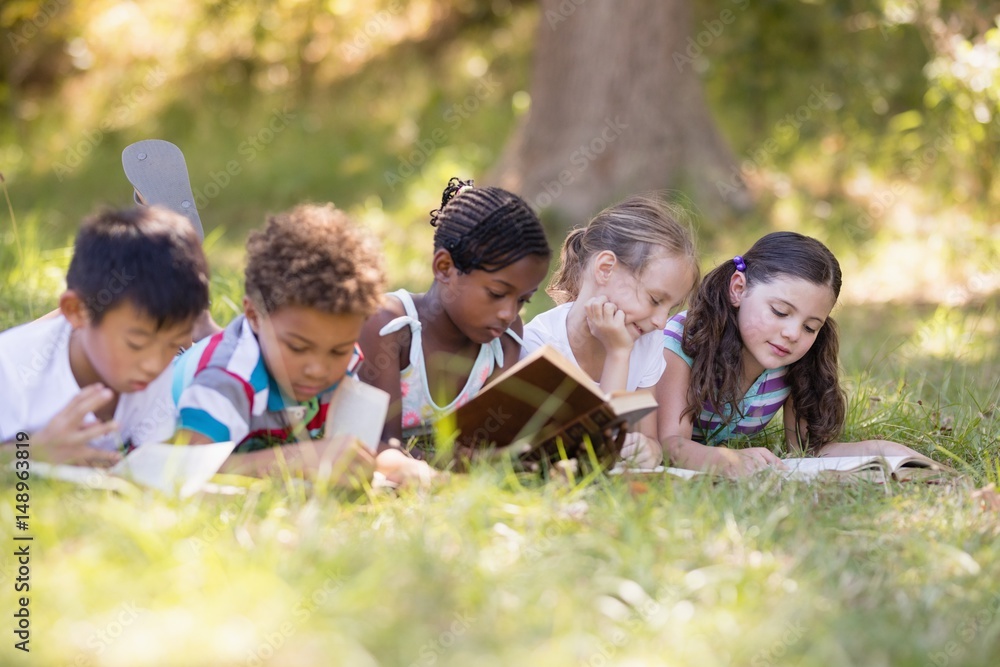 Group of friends reading book while lying on grassy field Group of friends reading book while lying on grassy field