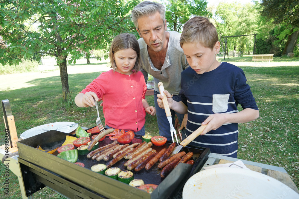 Obraz premium Father with kids preparing barbecue for family lunch