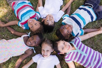 Smiling friends lying on grassy field in forest