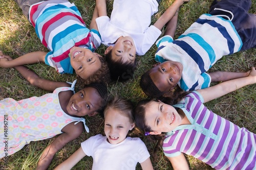 Smiling friends lying on grassy field in forest