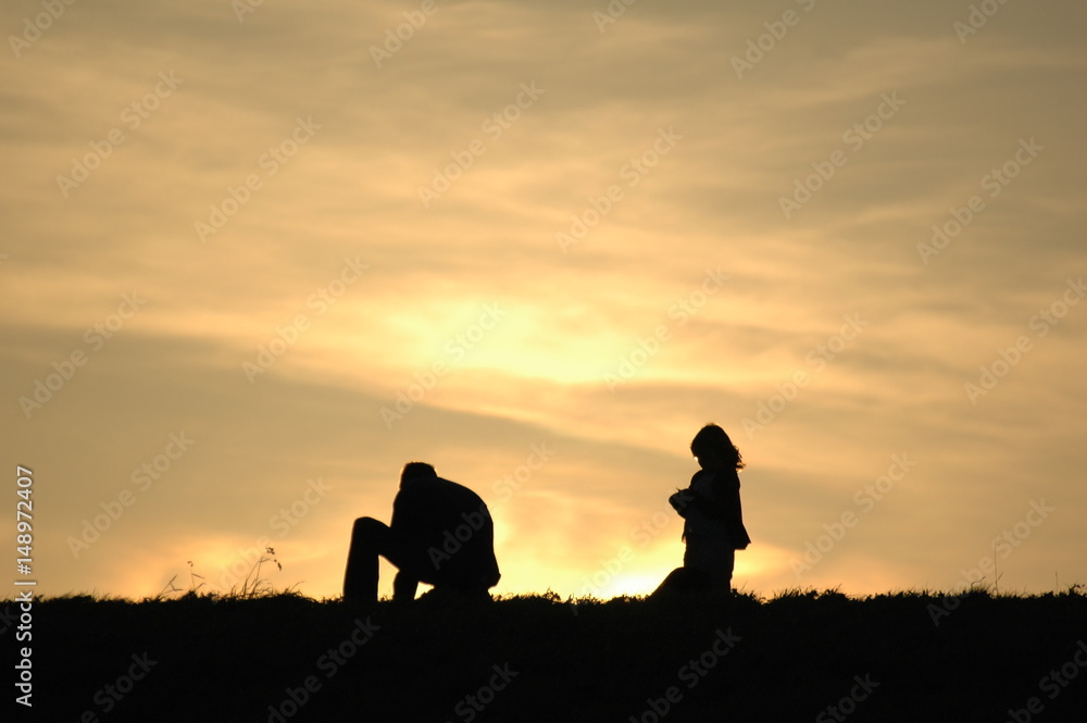 Vater mit Kind auf dem Damm im Sonnenuntergang