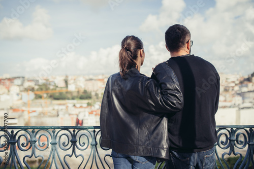 Young loving couple enjoying breathtaking view on Lisbon,Portugal from a miradouro on a sunny clear day.Honeymoon loving romantic couple traveling to charming european city for a romantic holiday  photo