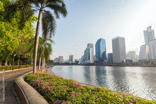 Jogging path, flowerbed and trees at the Benjakiti (Benjakitti) Park and modern skyscrapers in Bangkok, Thailand.