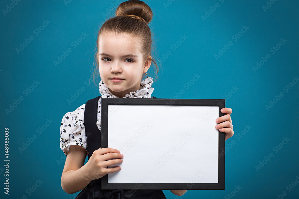 Cute little girl with a white sheet of paper. Isolated on blue background. Cute little girl with a white sheet of paper. Isolated on blue background.