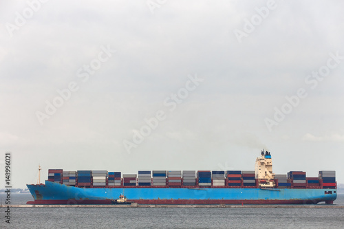 Cargo ship with tugboat maneuver to the port.