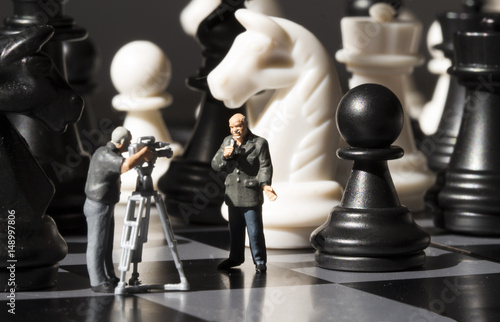 Chess news making. Filming chess game process. Miniature journalists on chessboard. photo