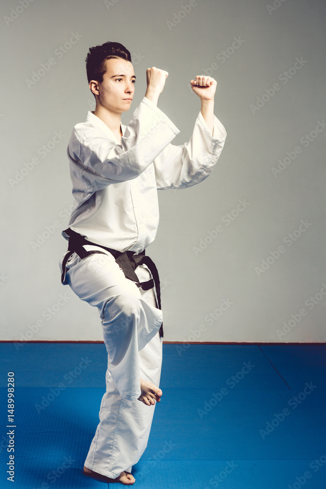 girl in karate suit kimono in studio at grey background. Female child shows judo or karate stans in white uniform with black belt. Individual martial art sport . body portrait girl in karate suit kimono in studio at grey background. Female child shows judo or karate stans in white uniform with black belt. Individual martial art sport . body portrait
