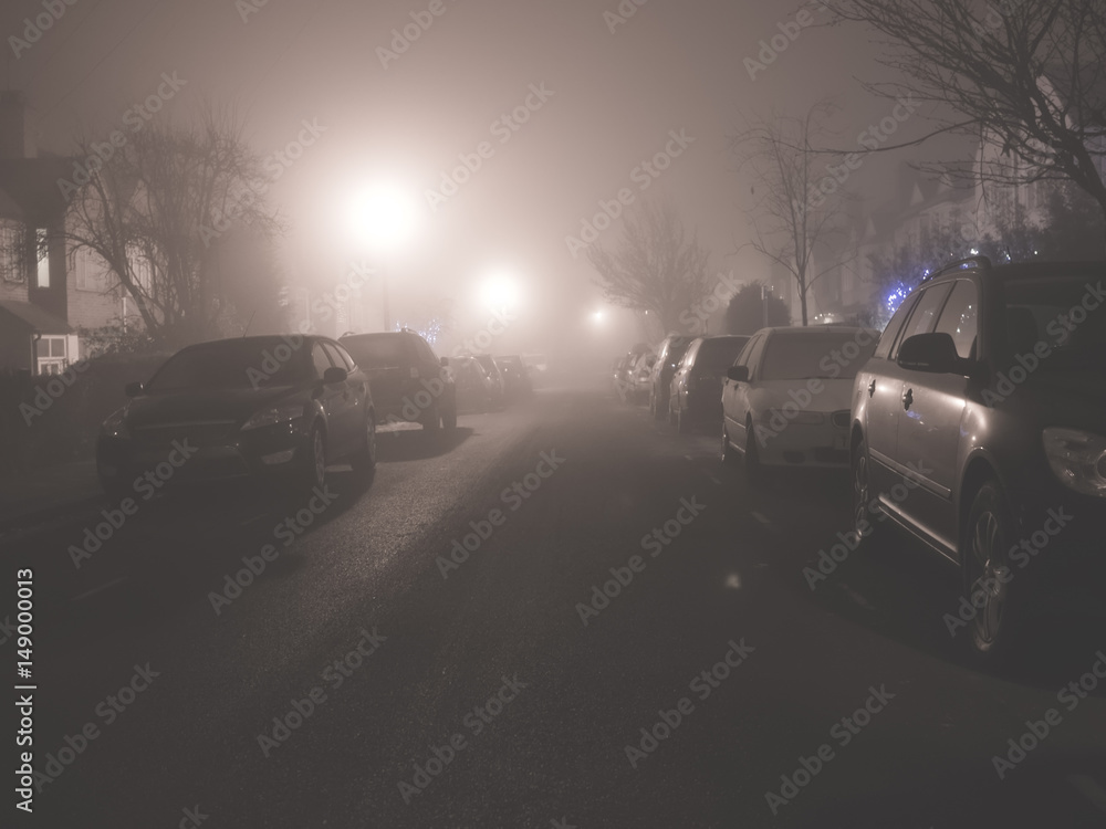 Parked cars in night time fog.