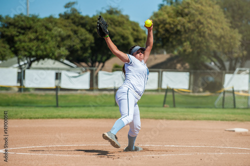 Canvastavla White uniform fast pitch softball pitcher winding up to throw in front view