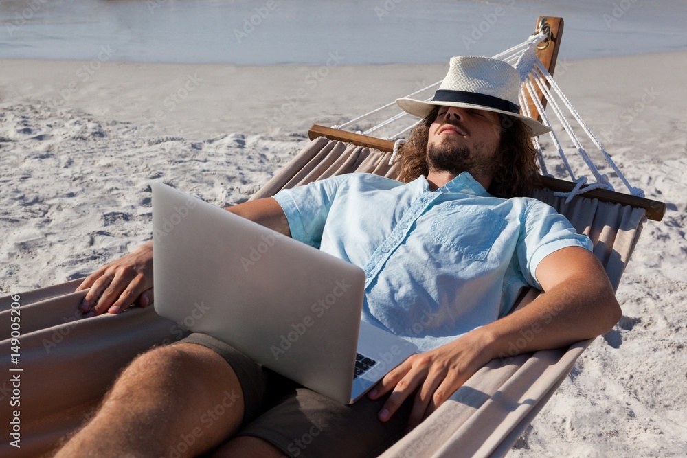 Man with laptop relaxing on hammock 
