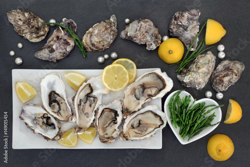 Oysters on crushed ice with lemon fruit, pearls and samphire  in a porcelain dishes on a slate.