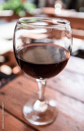 A glass of red wine on the vibrant restaurant background. Selective focus.