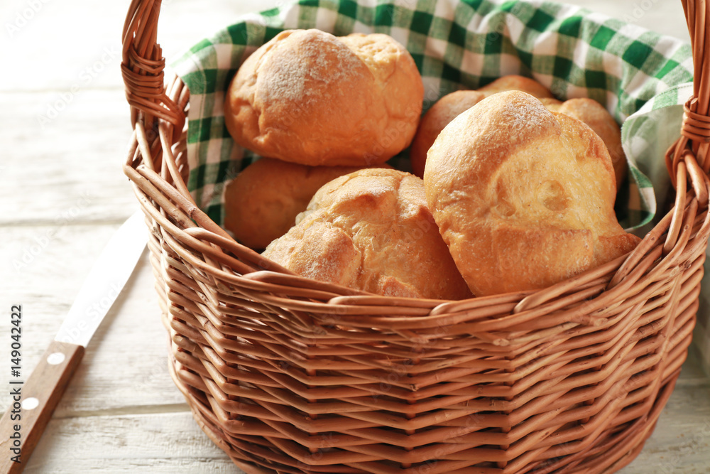Wicker basket with fresh tasty buns on table Wicker basket with fresh tasty buns on table
