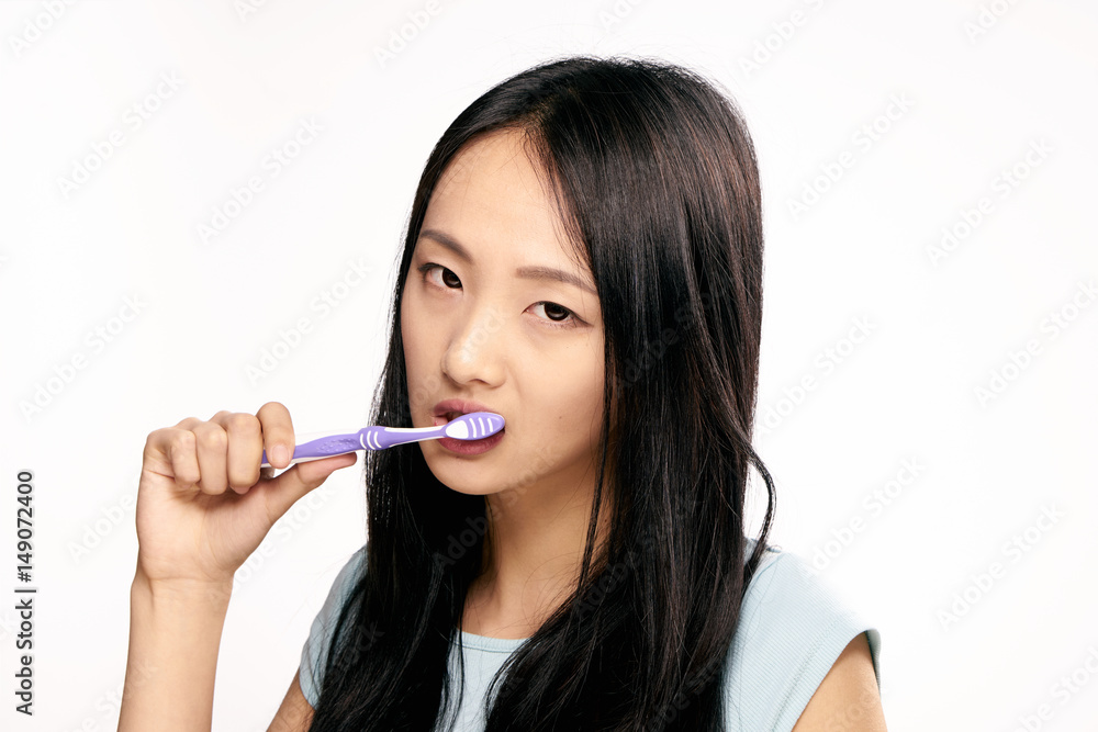 woman, narrow eyes, brush your teeth against a light background woman, narrow eyes, brush your teeth against a light background