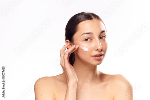 moisturizer on the face of a young woman, dark hair