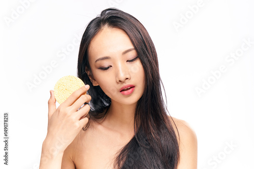 woman with sponge on a light background, brunette