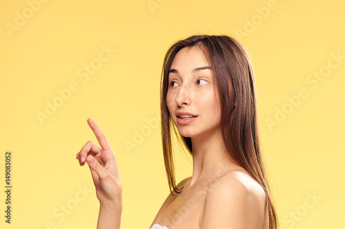 woman in a towel showing a finger to the side, yellow background